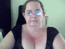 a woman wearing glasses and a black top is looking at the camera