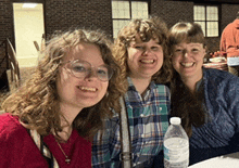 three women are posing for a picture with a bottle of water