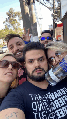 a group of people posing for a picture including a man wearing a black shirt that says trash