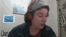 a woman wearing headphones and a hat is sitting in front of a computer .