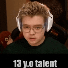 a young boy wearing headphones and glasses is sitting in front of a stuffed animal .