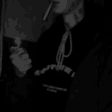 a man in a black hoodie is smoking a cigarette in a dark room .