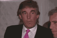 donald trump is wearing a pink tie and a mullet while standing next to a group of men .