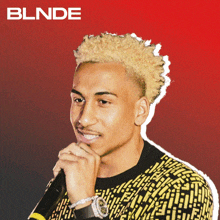 a man with blonde hair is holding a microphone in front of a red background that says blnde