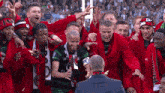 a group of soccer players are celebrating with a man in a suit and a scarf that says ' sport ' on it