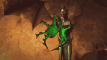 a statue of a demon with wings holding a green object