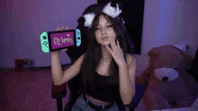 a girl holding up a nintendo switch with the number 02 written on the screen