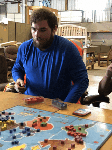 a man sits at a table playing a board game