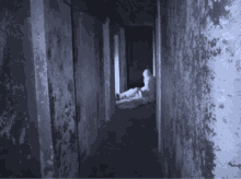 a person is sitting in a dark hallway with a blue light shining on them