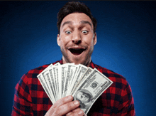 a man in a plaid shirt holds a bunch of money