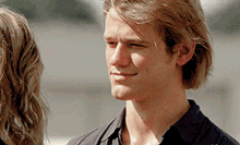 a young man with blonde hair is smiling and looking at a woman