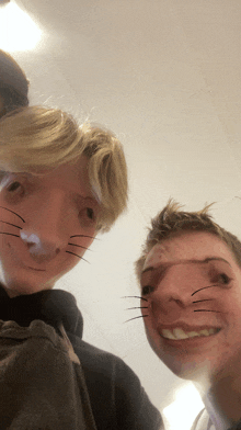 two young men with cat whiskers on their faces smile for the camera