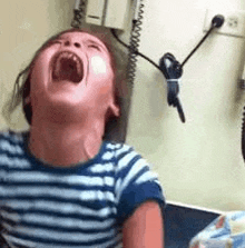 a little girl is screaming in a doctor 's office while sitting in a chair .