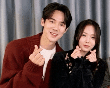 a man and a woman are posing for a picture and the man is wearing a red cardigan