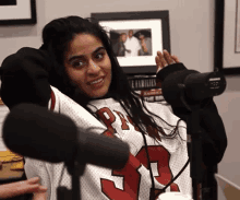 a woman wearing a jersey with the number 30 on it stands in front of a microphone .