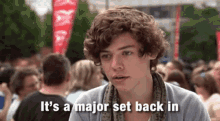 a young man with curly hair is sitting in front of a crowd and says it 's a major set back in