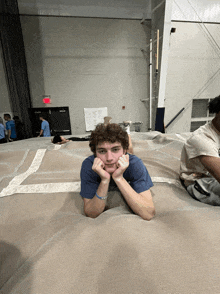 a young man laying on a blanket with his hands on his chin