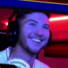 a man wearing headphones is smiling and looking at the camera in a dark room .