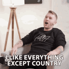 a man sitting on a couch with the words " i like everything except country " on the bottom