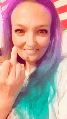 a woman with purple hair is making a middle finger sign .