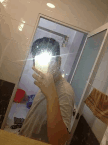 a man is taking a selfie in a bathroom mirror with his cell phone .