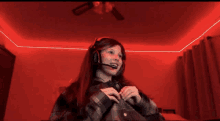 a girl wearing headphones and a microphone is sitting in a red room