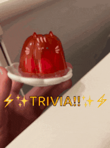 a person is holding a small red jelly on a white plate with the word trivia written on the bottom