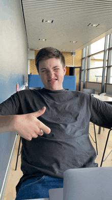 a young man wearing a black shirt is giving a thumbs up sign