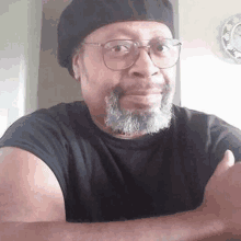 a man with a beard and glasses is wearing a beret and a black shirt .