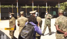 a group of soldiers wearing face masks are standing in a parking lot with a yellow sign that says bombo on the bottom