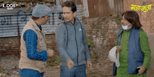 a group of men are standing in front of a brick wall and one of them is wearing a face mask