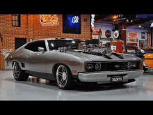 a silver ford mustang is parked in a garage next to a coca cola sign .