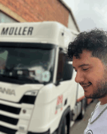 a man stands in front of a white truck that says muller on the side