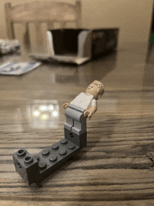 a lego figure is laying on a wooden table with a box in the background