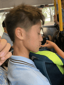 a boy sitting on a bus with his eyes closed and a yellow railing