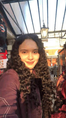 a girl with long curly hair is smiling in front of a sign that says ' chicago ' on it