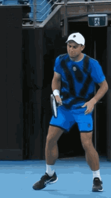 a man in a blue shirt and shorts is holding a tennis racket