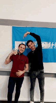 two men are posing for a picture in front of a blue banner that says ' champs '