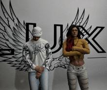 a man and a woman are standing in front of a wall with wings and the letter j on it