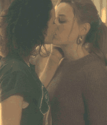 two women kissing with one wearing a t-shirt that says ' a ' on it