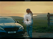 a man standing in front of a blue mercedes with a license plate that says fhte