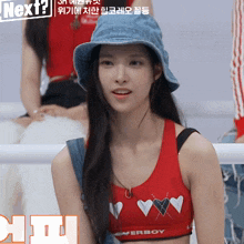 a girl wearing a hat and a red crop top with hearts on it