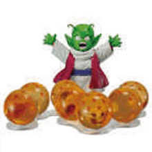 a figurine of piccolo from dragon ball z is standing next to a bunch of orange dragon balls .