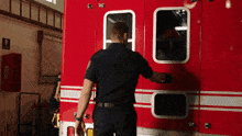 a man in a black uniform stands in front of a red fire truck with the word fire on it