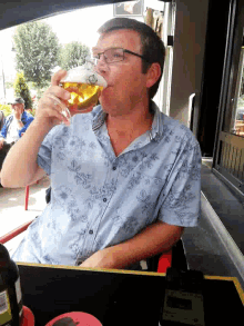 a man sitting at a table drinking from a glass with a label on it that says ' coca cola '