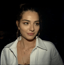 a woman wearing hoop earrings and a necklace with a letter a on it