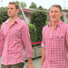 two men wearing red and white plaid shirts are standing next to each other in front of a soccer goal