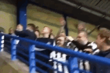 a group of people sitting in a stadium with a blue railing and a sign that says ' a ' on it