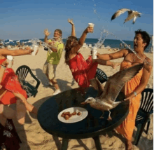 a group of people standing around a table on a beach