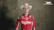 a race car driver wearing a cowboy hat and a red hy vee uniform